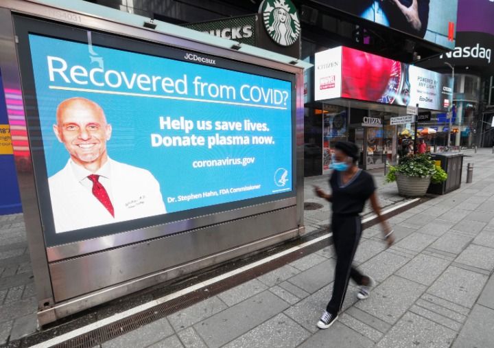 8月19日，在美国纽约，一名行人从号召新冠康复者捐献血浆的广告牌旁走过。新华社记者王迎摄