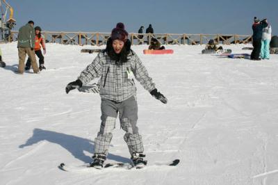 A snowboard beginner learns basic skills at the snowboarding school at Nanshan Ski Village. [Photo: CRIENGLISH.com]