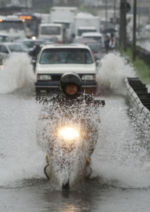 A motorcycle rider wades through a heavily flooded road in Sao Paulo, Brazil, Jan. 4, 2010. The continuous rainfall in recent days inundated many areas of the city. (Xinhua/AE)