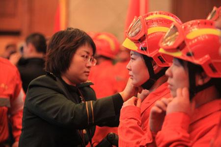 A female armed police official helps fastening helmet of a female member of a Chinese rescue team before the 50-member team's departure for quake-hit Haiti, at the Capital International Airport in Beijing, capital of China, Jan. 13, 2010. The team consist of search and rescue personnel, who have conducted many rescue tasks of this kind in the past years, and three sniffer dogs.(Xinhua/Xing Guangli)