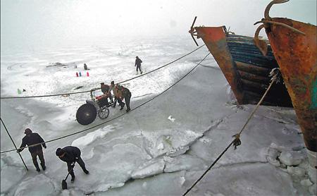 Fishermen in Jinzhou, Northeast China's Liaoning province, try to break the ice in the Bohai Sea on Monday. [Li Tiecheng/China Daily] 