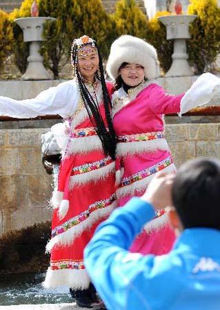 Tourists in local costumes pose for photos in Shangri-la County, Tibetan Autonomous Prefecture of Deqen, southwest China's Yunnan Province, March 12, 2010. Tibetan Autonomous Prefecture of Deqen attractted more than 4 millions tourists home and abroad in 2009. [Photo: Xinhua]