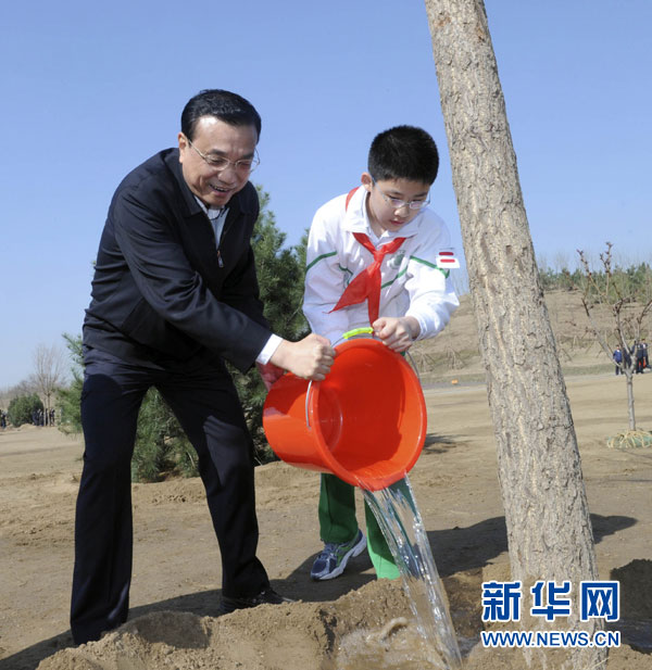 这是李克强同少先队员一起给树浇水。新华社记者 张铎 摄