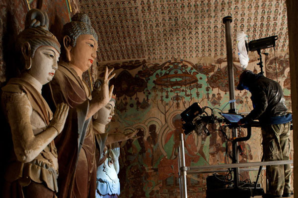 A photographer zooms in on a statue in a cave of Mogao Grottoes.Provided to China Daily