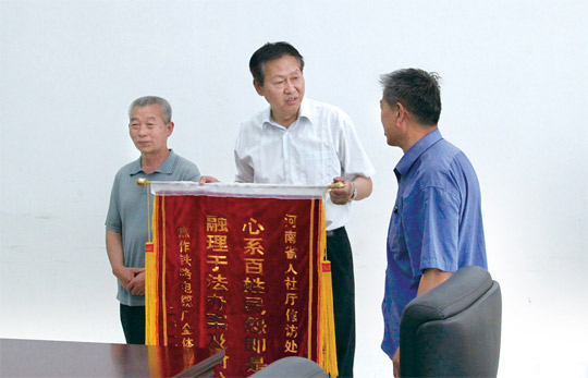 图为王宏（中）生前代表河南省人社厅接受群众赠送的锦旗。孙伟华 摄