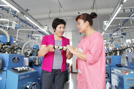 韩丽在袜厂与技术人员研究产品质量