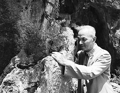 1957年6月，李四光在杭州飞来峰用放大镜察看石灰岩中的有孔虫化石。