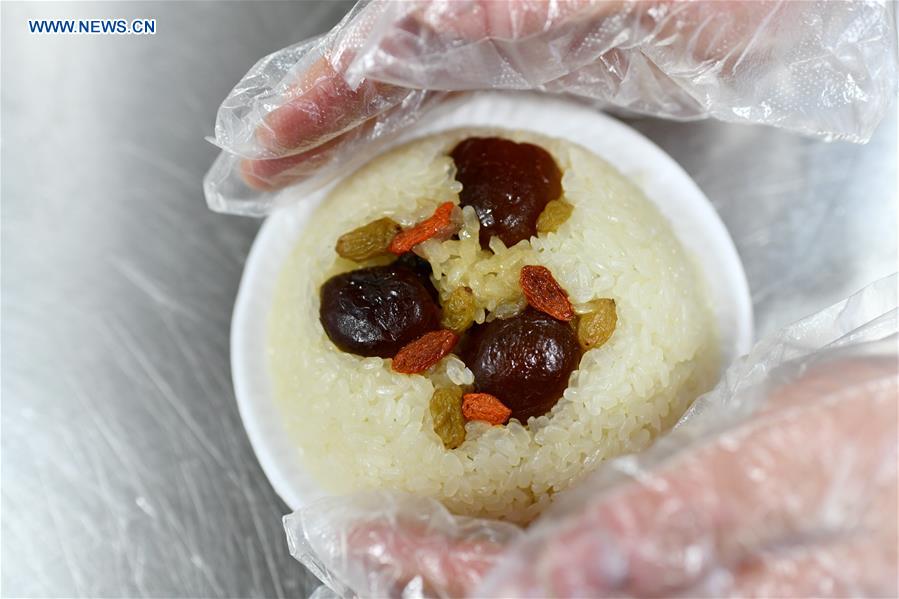 A worker holds a bowl of newly-steamed eight-treasure rice pudding at a workshop in Zunyi, southwest China