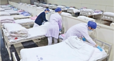      2月5日晚，首批新冠肺炎轻症患者开始入住武汉国际会展中心“方舱”。医务人员正在准备病床上的铺盖  