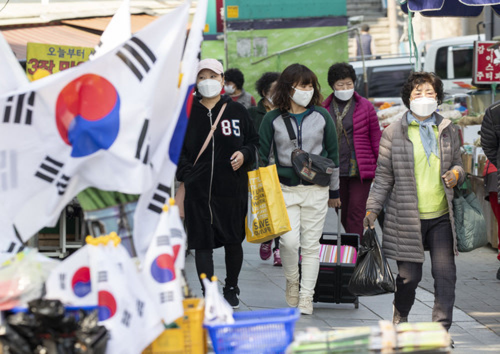 3月17日，在韩国大邱，人们佩戴口罩在西门市场附近出行。新华社发（李相浩摄）