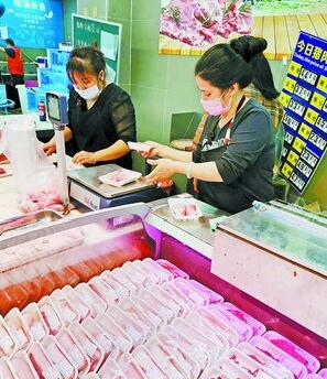 世纪华联生鲜超市(龙湖店)工作人员将一些切好的肉块放入塑料包装盒，连盒子一起称重。