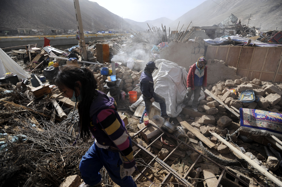 2010年4月18日，结古镇的几位受灾群众在废墟里收集自家的财产。新华社记者　江宏景　摄