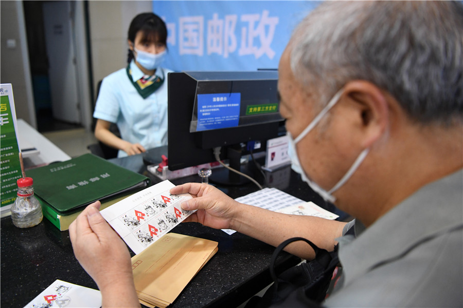 5月11日，在重庆解放碑主题邮局，集邮爱好者准备将《众志成城 抗击疫情》邮票粘贴到信封上。新华社记者 唐奕 摄