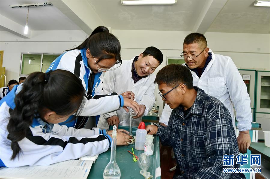 在西藏山南市第一高级中学，来自湖北省襄阳的援藏老师蔡春亭（中）和本地老师次仁曲旦（右后）指导学生做化学实验（2019年5月7日摄）。