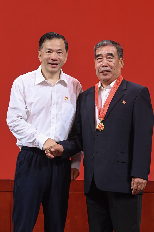 中宣部副部長、中央廣播電視總臺(tái)黨組書記、臺(tái)長慎海雄向“光榮在黨五十年”紀(jì)念章獲得者代表、新影集團(tuán)退休職工尤金華（右）頒發(fā)紀(jì)念章