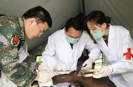 Wang Yurong (1st L), head of a Chinese medical team, works with two other team members on the wound of an injured man at a makeshift hospital that the team has set up in Port-au-Prince Jan. 27, 2010. The team will stay in Haiti for weeks to provide basic medical care for survivors of the Jan. 12 earthquake. (Xinhua Photo)