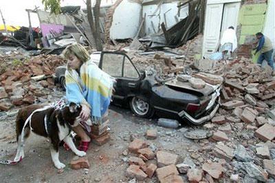 A woman sits in front a quake-damaged house in Talca, Chile, after a 8.8-magnitude earthquake struck the country early Saturday, Feb. 27, 2010. (AP Photo/Sebastian Martinez)