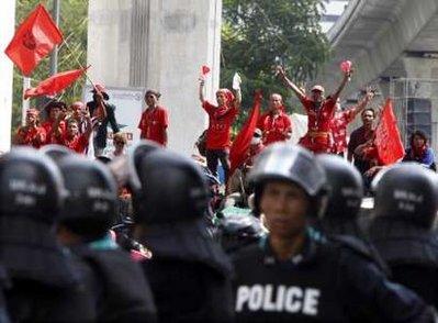 Anti-government "red shirt" protesters waves red flags as they stand on top of a barricade built with bamboo poles and tyres facing riot police at an intersection close to the Silom Road financial district in Bangkok April 21, 2010. Thai anti-government protesters fortified their main rally site in an upmarket shopping area of Bangkok after the government warned they would be evicted, setting up a potentially bloody clash in the capital.REUTERS/Eric Gaillard