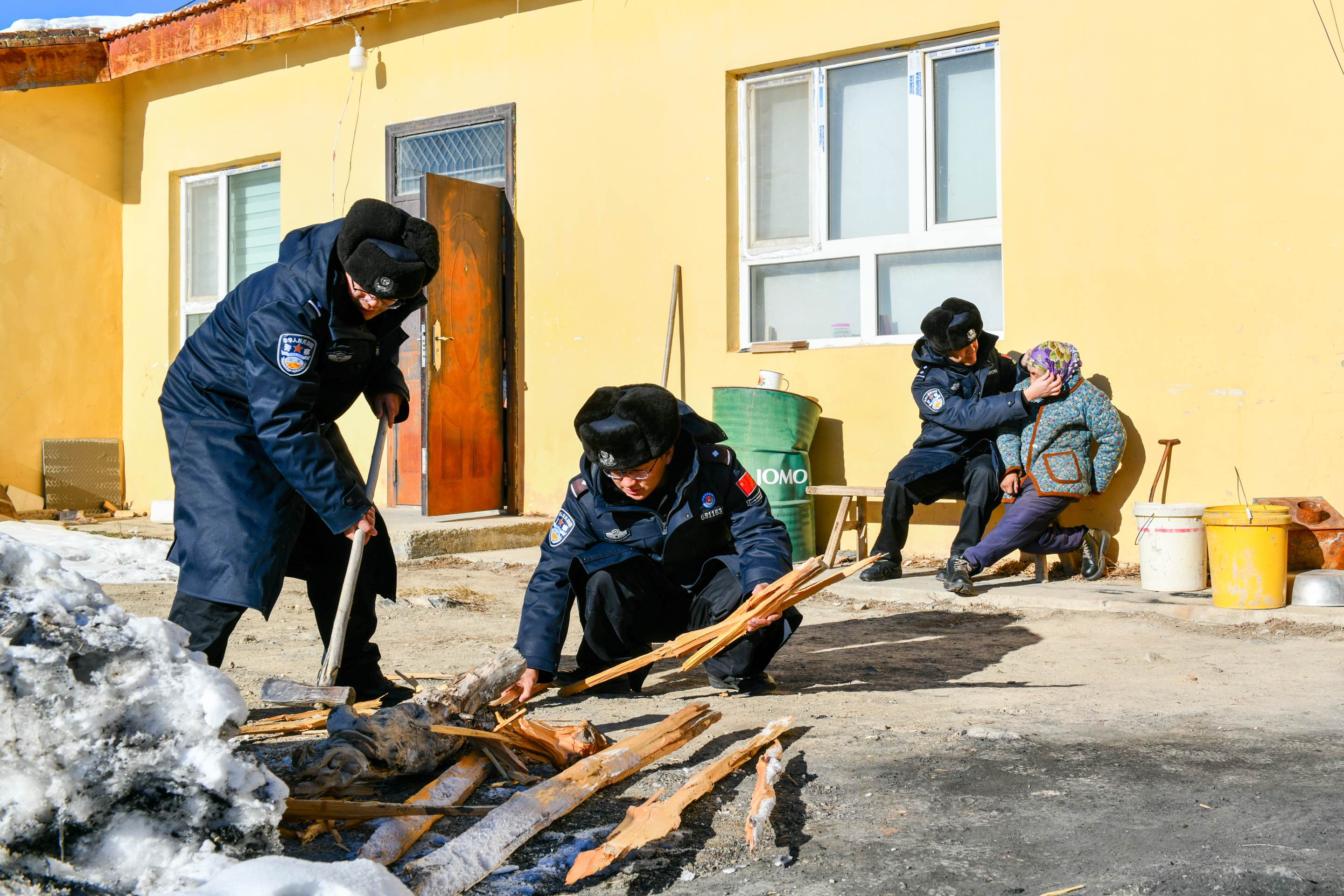 图为民警帮助托乎提汗亚热老人劈柴