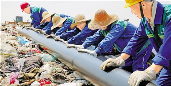 顶37度酷暑踩10斤重胶鞋 铺膜工每天为4千吨垃圾穿衣