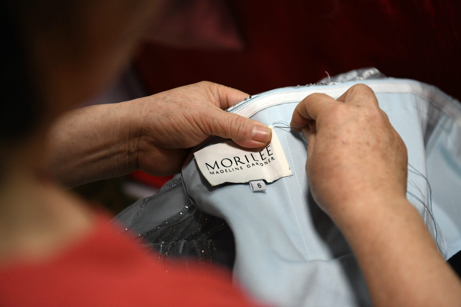 An embroiderer sews a brand label onto a Morilee dress at a factory in Chaozhou, south China