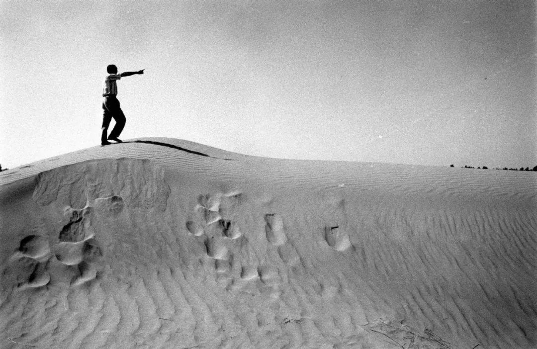 1997年，石光银指着新承包的荒漠说：“两三年后，这里也是一片绿洲。”图／新华社发　陶明　摄