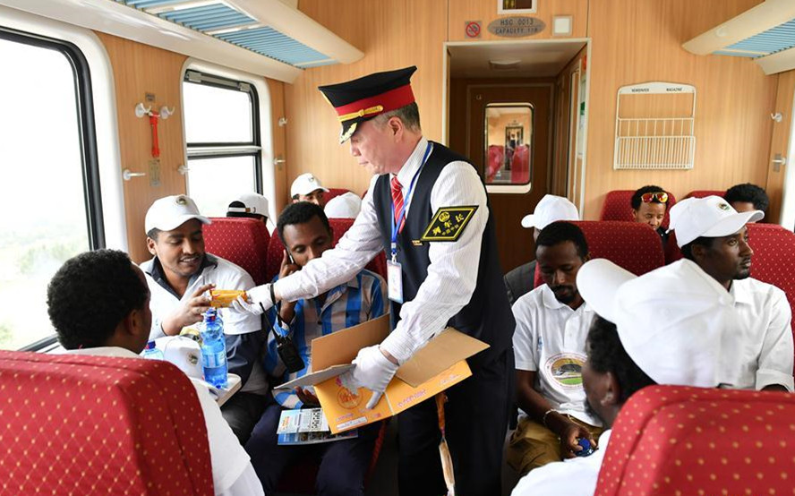 Li Chenglin (C), head of the train crew, gives cookies to passengers on a passenger train of Ethiopia-Djibouti railway in Ethiopia, on Oct. 5, 2016. 