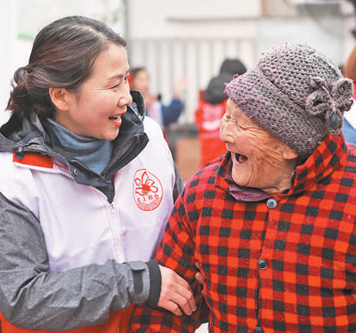 邓红（左）在养老院看望老人。资料照片
