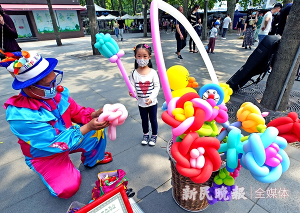 图说:刘振胜为小朋友表演扎气球花 资料图 郭新洋 摄