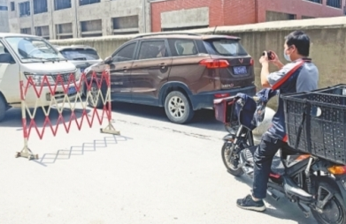 叶元晨用手机拍照记录车辆堵塞交通的不文明现象。