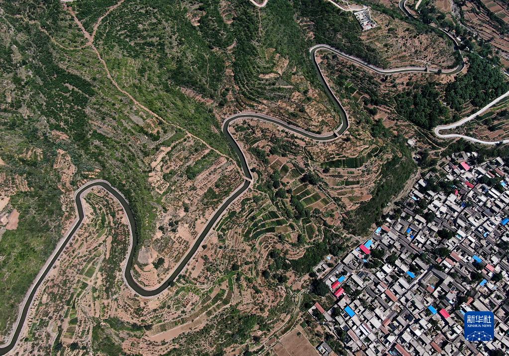 红旗渠总干渠从一座村庄旁绕过（2019年7月5日摄，无人机照片）。新华社记者 李安 摄
