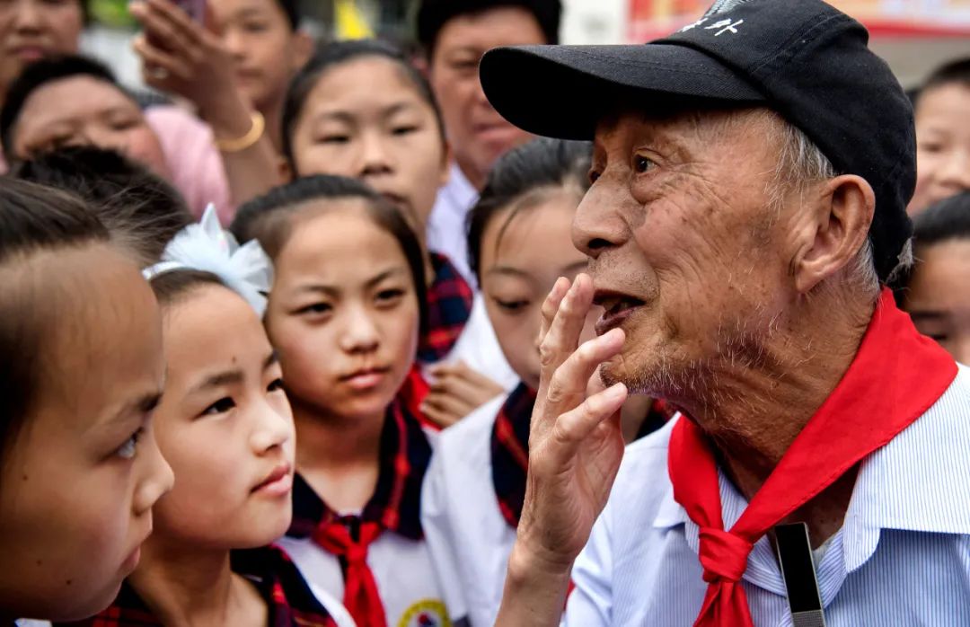 2018年5月19日，周火生老人（前右）与金寨县希望小学的孩子们在一起交谈。新华社记者 陶明 摄