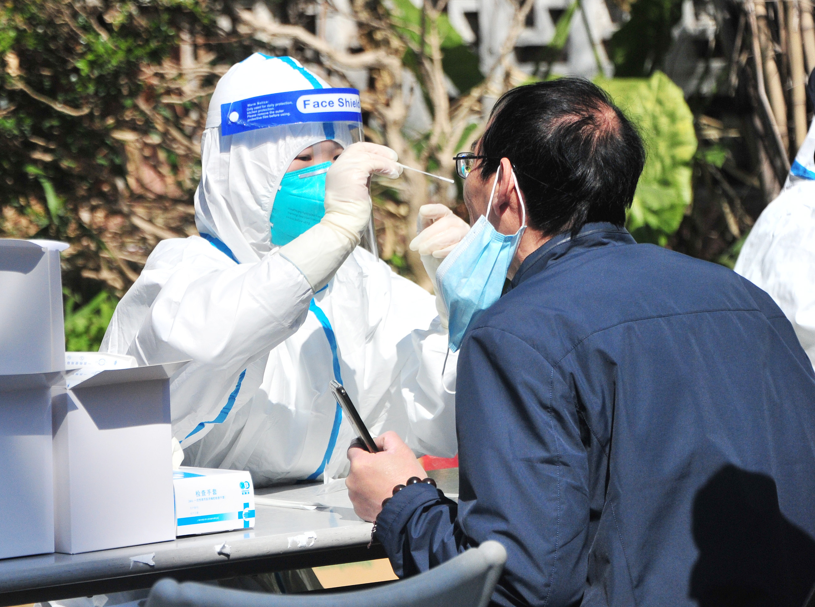 2022年3月7日，上海，社区内，医护人员给市民做核酸检测采样。