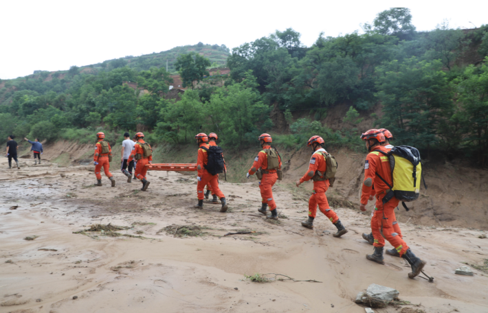 7月16日，甘肃省庆阳市庆城县翟家河乡消防救援人员在当地向导带领下寻找被困人员。（甘肃省森林消防总队平凉支队供图）