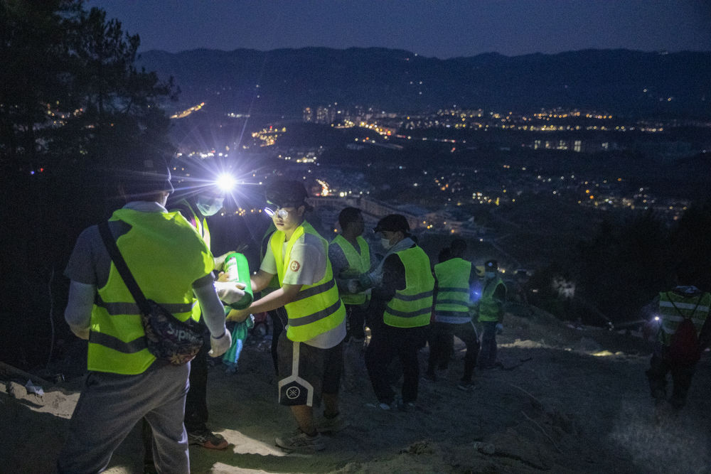 8月25日晚，在重庆市北碚区缙云山，志愿者排成的“人链”在接力往山上传送灭火救援物资。