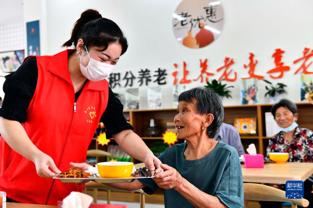 在山东省日照市岚山区安东卫街道凤凰山社区养老服务中心，志愿者为社区老人端来午餐（2021年9月4日摄）。