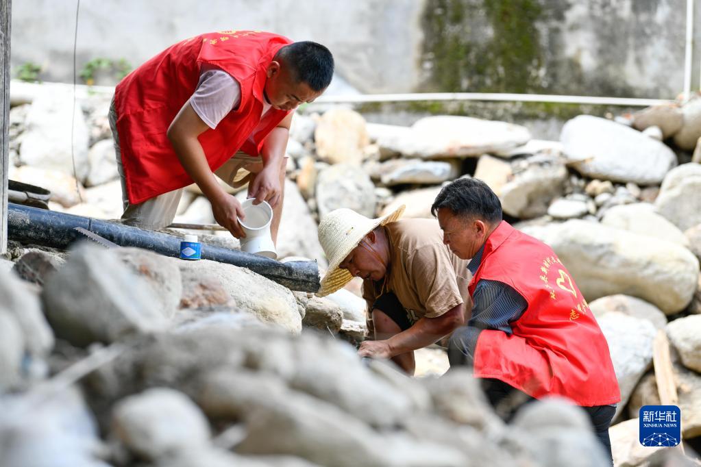 在贵州省黔东南苗族侗族自治州从江县刚边壮族乡银平村，党员志愿者帮助遭受强降雨袭击受灾的村民修整水管（2022年7月1日摄）。