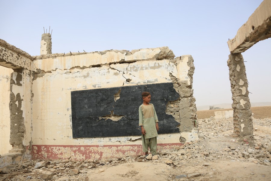 A boy stands in the ruins caused by U.S. air strikes in Sangin district of Helmand Province, Afghanistan, Aug. 23, 2022. (Photo by Saifurahman Safi/Xinhua)