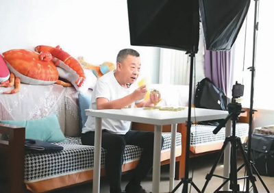 美食博主“结巴老爹”在家中拍摄品尝美食的短视频。新华社记者姚剑锋摄
