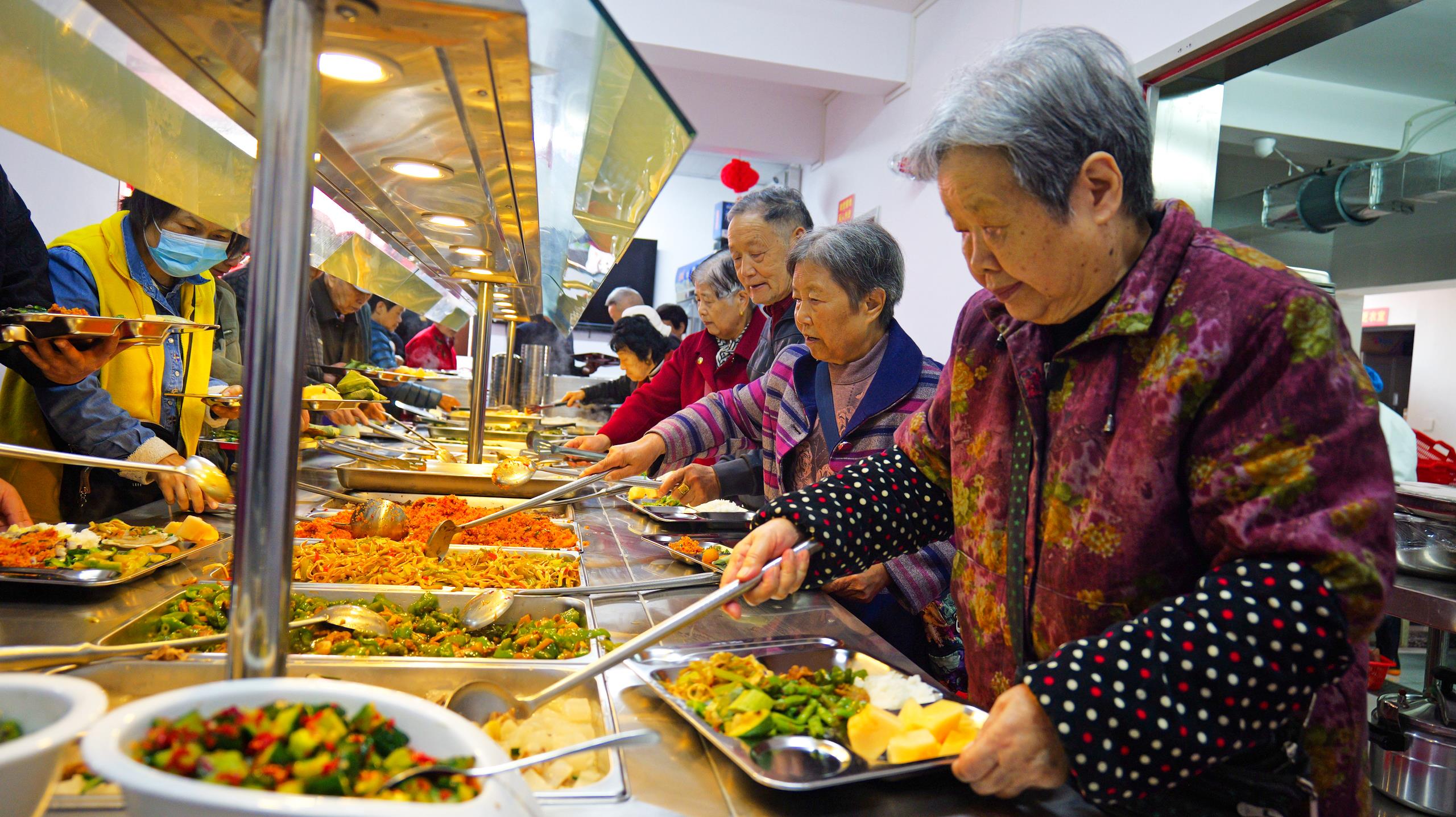 △湖北恩施一社区“幸福食堂”里，社区老人、退休职工在排队取餐。