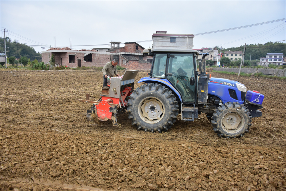 农机手将肥料、油菜种子等放入机器，实现旋耕、碎土、开沟、播种、施肥、封闭除草“六位一体”高效作业。